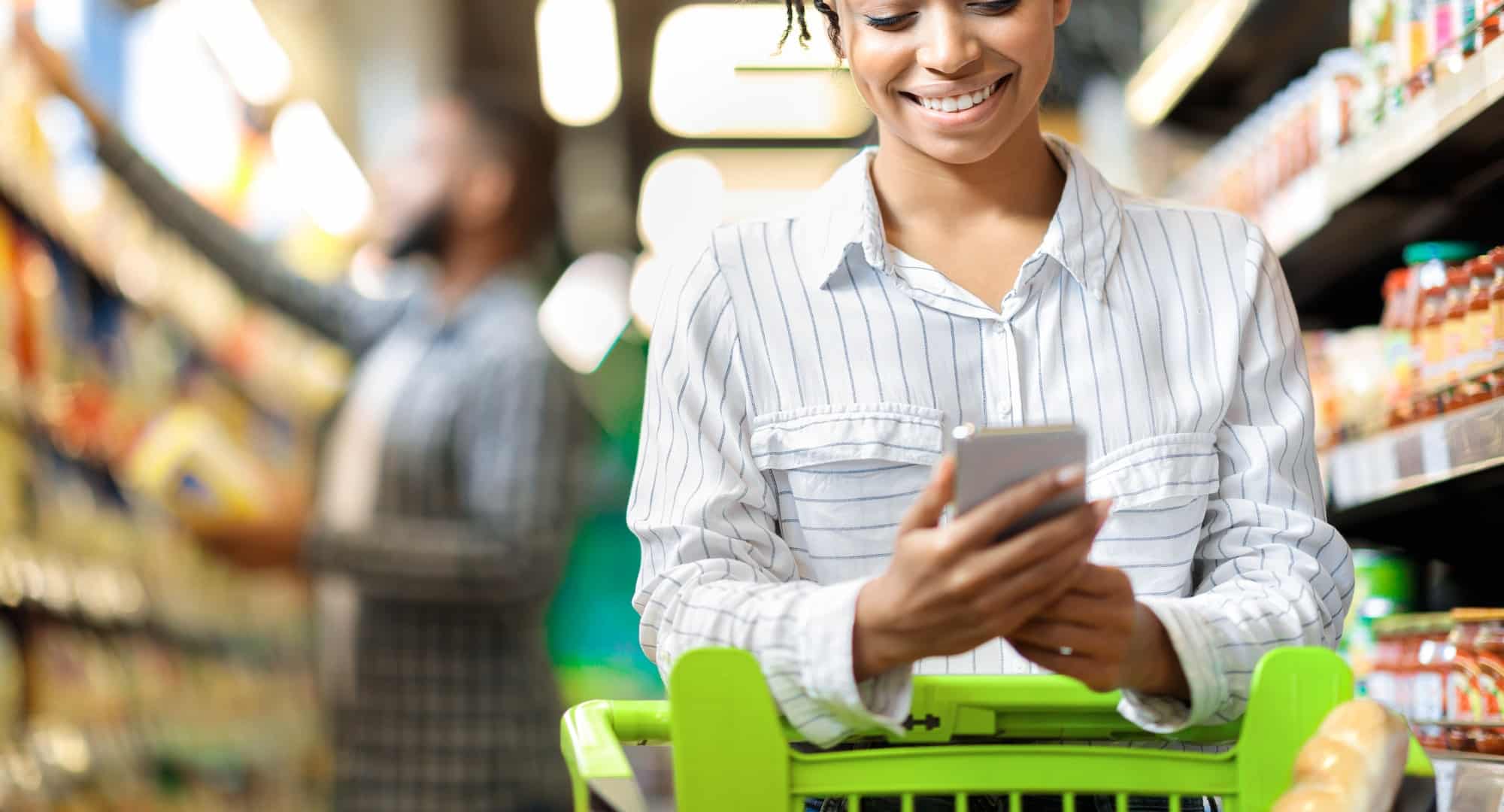 African Woman Using Grocery Shopping App On Smartphone In Supermarket