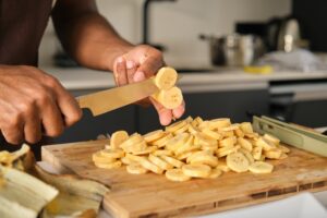 Unrecognizable young black man cutting plantains.